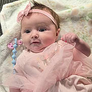 Pyper is registered to the contest to win money with this photo: baby, infant, pink_dress, headband, blanket, pacifier_clip, clothing, cute, child, portrait, lying_down, soft_toys, indoors, person, newborn, adorable, happy, small_hand, face, young