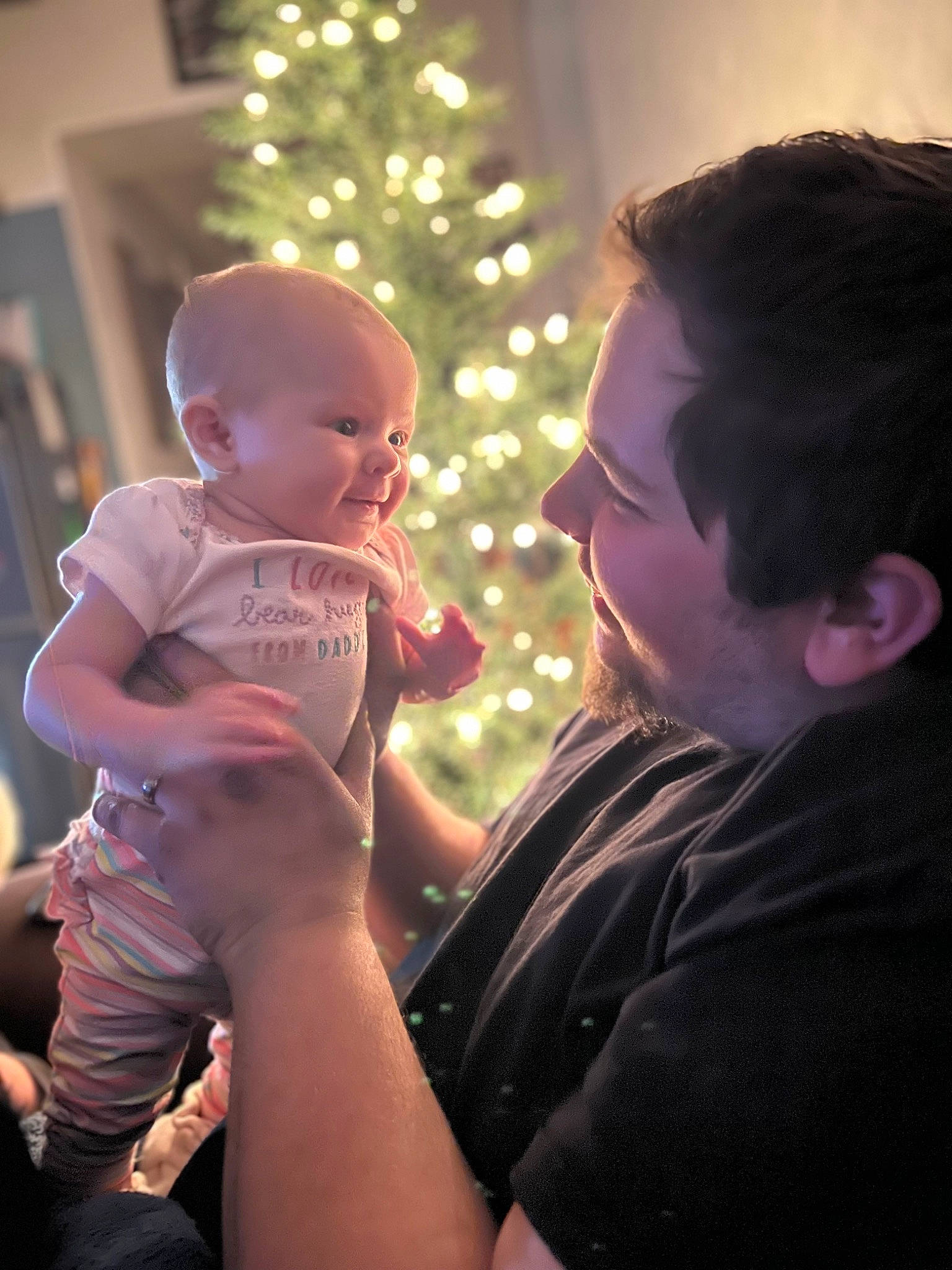 Paisley Rae joined the competition — help win amazing prizes! arm, baby, child, christmas_ornament, christmas_tree, ear, event, fun, gesture, hairstyle, happy, holiday, human, human_body, interaction, lap, person, sitting, t_shirt, toddler