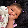 baby, child, infant, portrait, smiling, awake, hand, fist, pony_tail, hair, pink_clothing, blanket, floral_pattern, plush_toy, bunny, soft_blanket, cozy, lying_down, indoor, close_up