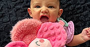 Julietta is registered to the contest to win money with this photo: baby, baby_clothing, blanket, bracelet, child, close_up, cute, dark_background, hand, headband, indoor, infant, lying_down, open_mouth, pink, plush_toy, portrait, smiling, stuffed_flower, surprised