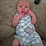 Bentley joined the competition — help win amazing prizes! baby, baby_bottles, blanket, blue_outfit, checkered_pattern, couch, curious_expression, eyes, face, fingers, hand, human, indoor, infant, newborn, remote_control, sitting, skin, texture, whale_patch