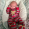 baby, newborn, infant, onesie, striped_clothing, red_clothing, gray_clothing, baby_seat, cushion, patterned_background, face, head, hands, feet, sleepwear, cute, child, indoors, person, resting