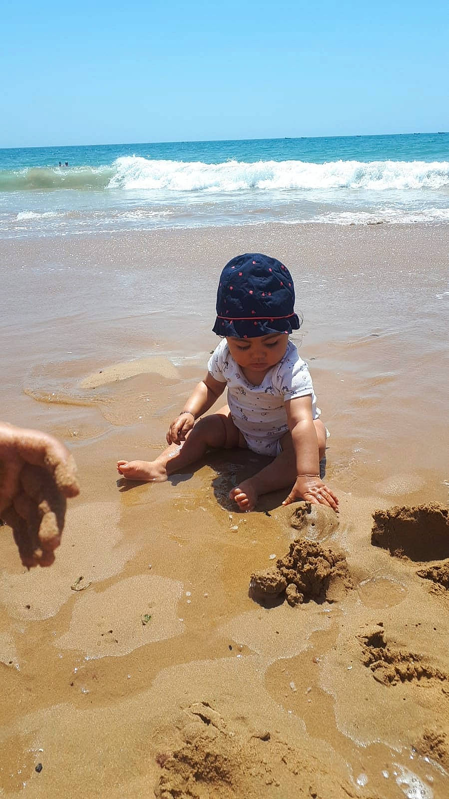 Maïssa a rejoint le concours — aidez-le/la à gagner de superbes lots ! beach, child, coastal_and_oceanic_landforms, fun, hat, headwear, horizon, landscape, mammal, morning, people_in_nature, people_on_beach, person, recreation, sand, shore, sky, toddler, vertebrate, water