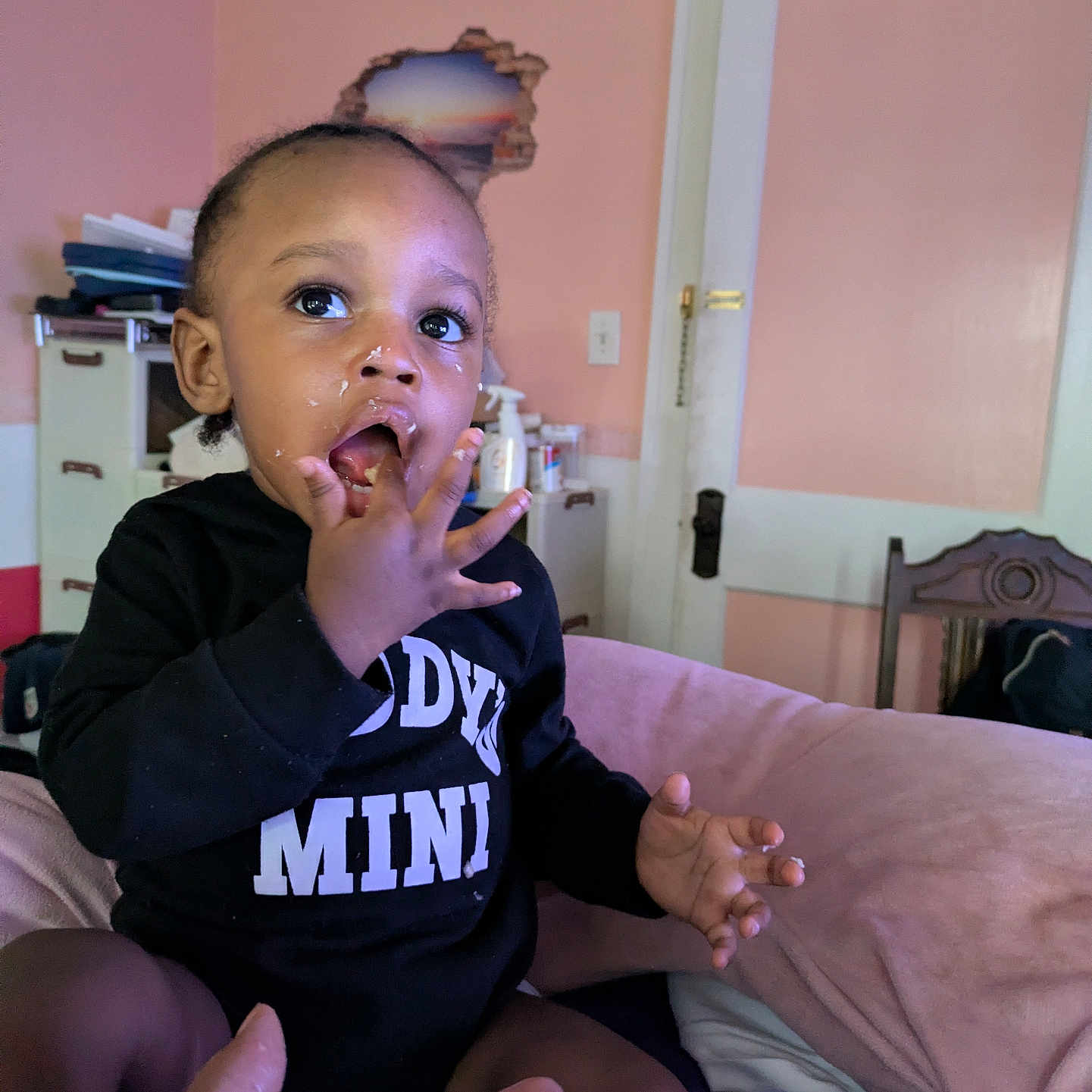 Daron joined the competition — help win amazing prizes! black_outfit, cabinet, child, clothing, curious, door, expression, face, feeding, fingers, food, furniture, hand, indoor, mouth, person, pink_wall, room, sitting, toddler