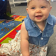 Sadie joined the competition — help win amazing prizes! baby, child, smiling, flower_headband, denim_vest, floral_dress, crawling, indoor, carpet, colorful_rug, toy, person, happy, face, footwear, education, playroom, cute, young_child, hand