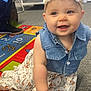 baby, child, smiling, flower_headband, denim_vest, floral_dress, crawling, indoor, carpet, colorful_rug, toy, person, happy, face, footwear, education, playroom, cute, young_child, hand