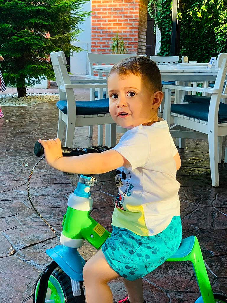 Luca is registered to the contest to win money with this photo: baby_toddler_clothing, chair, child, electric_blue, grass, happy, human_leg, leisure, outdoor_furniture, person, photograph, plant, shorts, sitting, smile, snapshot, summer, thigh, tire, toddler