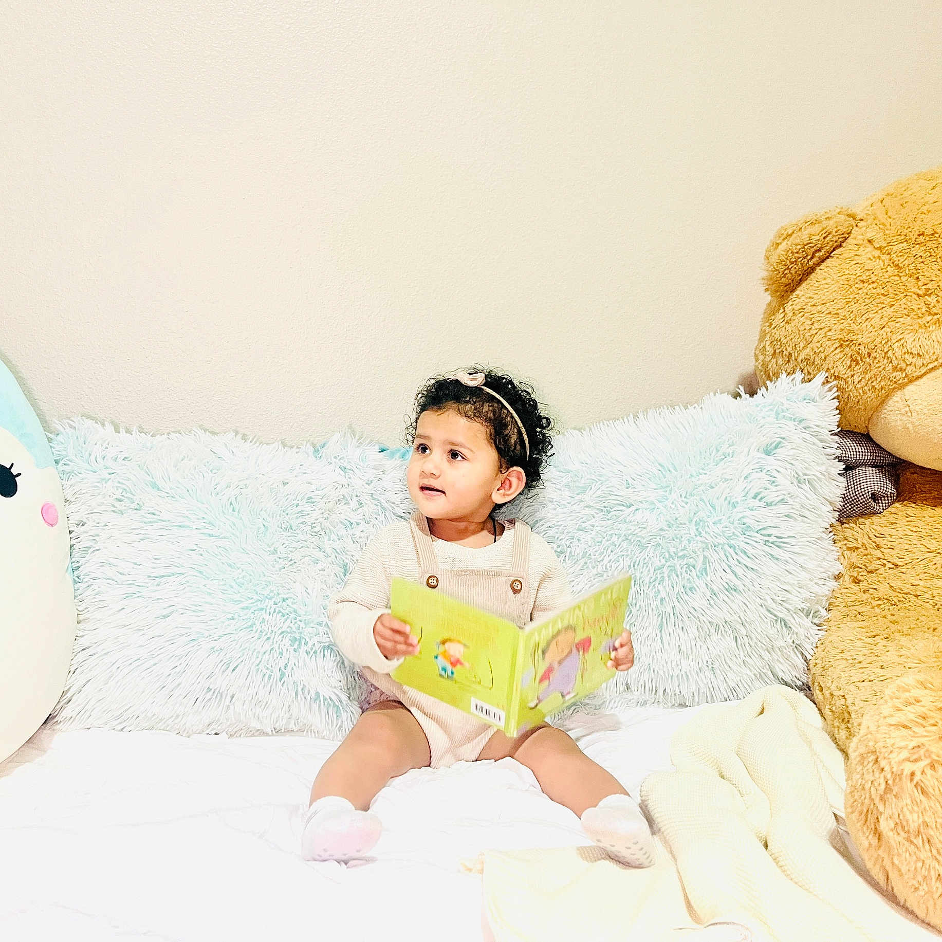 Nia joined the competition — help win amazing prizes! bed, book, child, cozy, curly_hair, cushion, cute, happy, headband, indoor, light, pillow, playful, plush_toy, portrait, reading, socks, soft, stuffed_animal, toddler