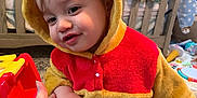 Declan is registered to the contest to win money with this photo: toddler, child, hoodie, yellow, red, hand, holding, baby, nursery, toys, clothing, indoor, person, cute, smiling, face, baby_furniture, carpet, hand_holding, plush