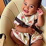 baby, child, smiling, high_chair, pink_bows, dress, embroidery, happy, cute, indoors, seatbelt, playful, toddler, skin, foot, hand, face, person, furniture, window