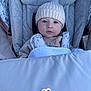 baby, child, stroller, hat, knit_hat, blue_eyes, face, infant, outdoor, warm_clothing, padded_seat, blanket, person, cute, portrait, baby_clothes, bundle_up, seat_belt, baby_boy, infant_care