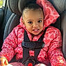 child, toddler, car_seat, pink_jacket, heart_pattern, safety_harness, smiling, happy, indoors, seat_belt, car, sunlight, young_child, cute, portrait, clothing, hair_puff, seat, baby, casual