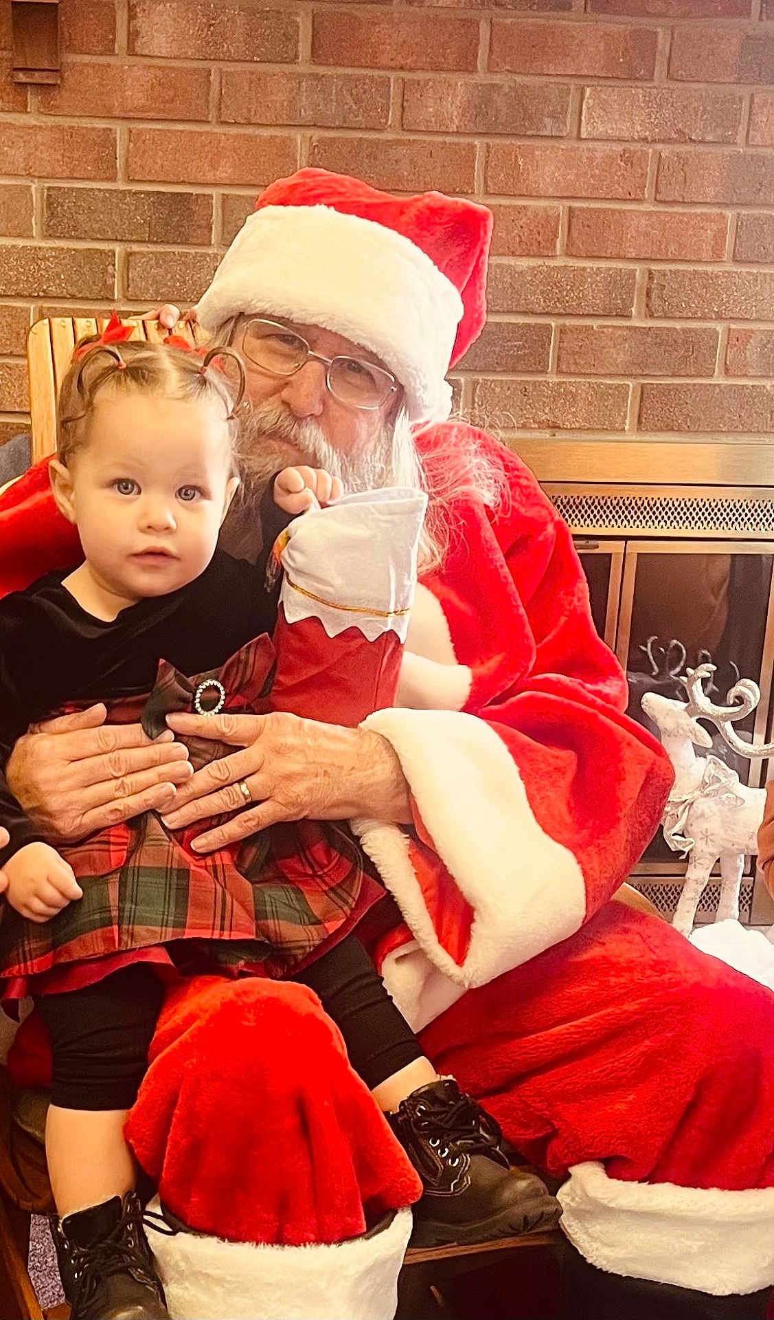 Lynnlee is registered to the contest to win money with this photo: child, toddler, santa_claus, holiday, christmas, stocking, plaid_dress, braided_hair, boots, fireplace, brick_wall, glasses, beard, red_suit, indoor, festive, smile, person, celebration, holding