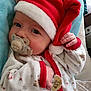 baby, pacifier, santa_hat, holiday_pajamas, blanket, infant, cute, sleepy, hand, face, clothing, red_trim, white_fabric, patterned_fabric, indoors, portrait, child, newborn, soft_texture, cozy