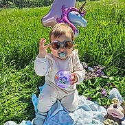 Mya participe au concours pour gagner de l'argent avec cette photo : baby, balloon, birthday, blanket, celebration, child, cute, flower, grass, greenery, happy, number_one, outdoor, pacifier, plush_toy, purple_ball, sunglasses, sunny, toy, unicorn