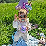 baby, balloon, birthday, blanket, celebration, child, cute, flower, grass, greenery, happy, number_one, outdoor, pacifier, plush_toy, purple_ball, sunglasses, sunny, toy, unicorn