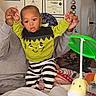 Mason joined the competition — help win amazing prizes! baby, child, infant, smiling, surprised, sitting, indoor, portrait, person, face, hands, adult, holding, monster_costume, green_clothing, striped_pants, blanket, plush_toy, giraffe, certificates