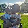 baby, infant, child, adult, parent, 抱抱, portrait, outdoor, park, stroller, family, holding, sitting, sunlight, backlighting, grass, trees, bench, blue_shirt, striped_sock