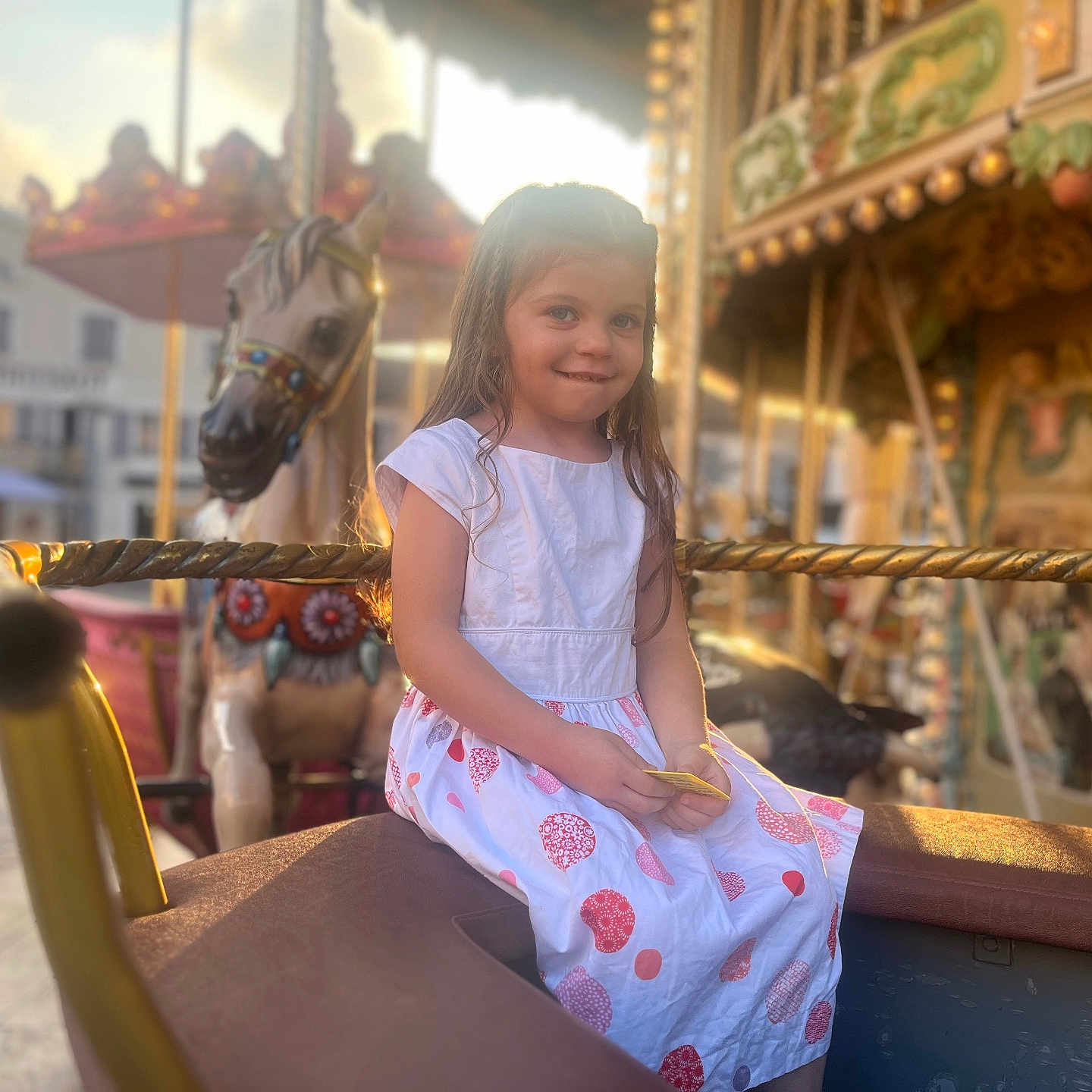 Alia a rejoint le concours — aidez-le/la à gagner de superbes lots ! amusement_park, blurred_background, carousel, child, colorful, dress, festival, fun, girl, happy, horse, long_hair, outdoor, person, playful, ride, seat, smile, summer, sunlight