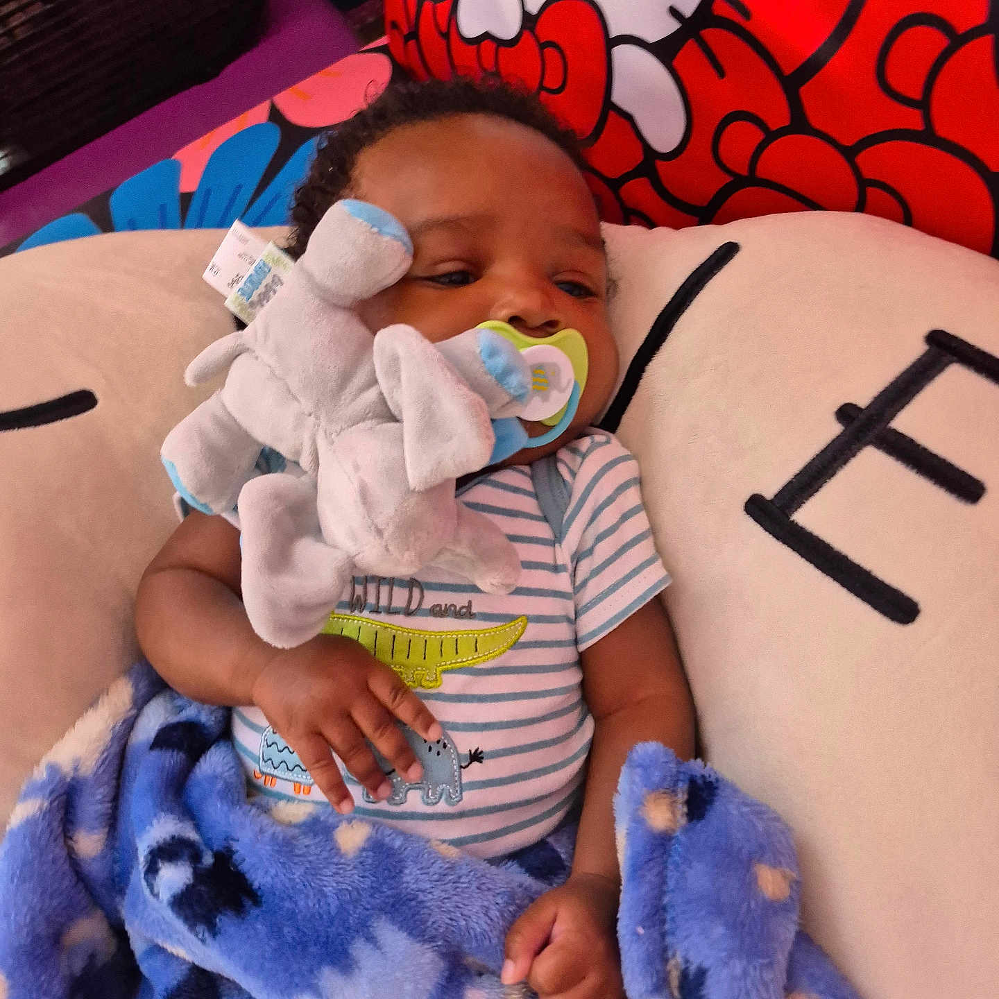 Isiah is registered to the contest to win money with this photo: baby, blanket, blue_blanket, child, closeup, comfort, cushion, cute, elephant_toy, fabric, hand, hello_kitty, indoor, infant, pacifier, plush_toy, resting, sleepy, soft_toy, striped_onesie