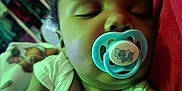 Isiah is registered to the contest to win money with this photo: baby, sleeping, pacifier, elephant, infant, closeup, face, child, pillow, white_clothing, arm, indoors, rest, peaceful, portrait, cute, soft_lighting, relaxation, toddler, sleep