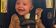 Octavia is registered to the contest to win money with this photo: baby, car_seat, smiling, child, safety_harness, infant, seat_belt, clothing, happy, portrait, indoor, warning_label, cute, person, head, face, sitting, young_child, secured, infant_clothing
