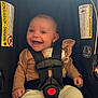 baby, car_seat, smiling, child, safety_harness, infant, seat_belt, clothing, happy, portrait, indoor, warning_label, cute, person, head, face, sitting, young_child, secured, infant_clothing