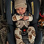 baby, infant, car_seat, hat, pajamas, smiling, tongue_out, cozy, plush, child, straps, safety, cute, indoor, fabric, warm_clothing, football_pattern, headgear, seat, happy