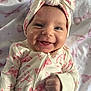 baby, infant, smile, smiling, headband, bow, onesie, bow_pattern, blanket, bed, portrait, close_up, cheek, fist, hand, eyes, teething, cute, skin, happy