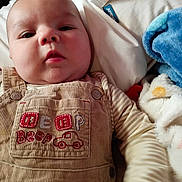 Jackson joined the competition — help win amazing prizes! baby, bed, blanket, child, closeup, clothing, cozy, cute, expression, fabric, face, indoor, infant, overalls, plush_toy, portrait, sleeping_area, soft_toy, striped_shirt, young_child