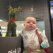 Jackson joined the competition — help win amazing prizes! baby, infant, child, person, pajamas, star_wars, baby_clothes, reindeer, plant_decor, red_bow, hand, pick_up_sign, indoor, fast_food, menu, wall, tile, cute, holding, curious