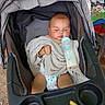 baby, stroller, milk_bottle, towel, diaper, sleeping, child, food, snack, outdoor, seat, baby_bottle, infant, resting, cute, baby_clothing, young_child, feeding, person, relaxing