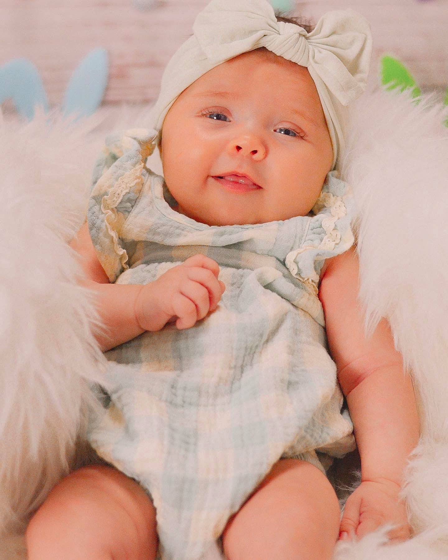 Naomi is registered to the contest to win money with this photo: baby, baby_toddler_clothing, cap, cheek, comfort, gesture, grass, happy, hat, head, headwear, iris, lip, person, pink, sitting, skin, sleeve, smile, thumb