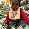 baby, child, smiling, sitting, bib, clothing, indoor, bed, blanket, pillow, footwear, socks, person, happy, cute, infant, red_sweater, denim_pants, home, portrait