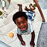 toddler, child, smiling, playmat, toy, lion_toy, orange_ball, wooden_play_gym, carpet, indoor, cute, happy, baby_clothing, shorts, white_shirt, african_american, infant, floor_play, early_childhood, cheerful