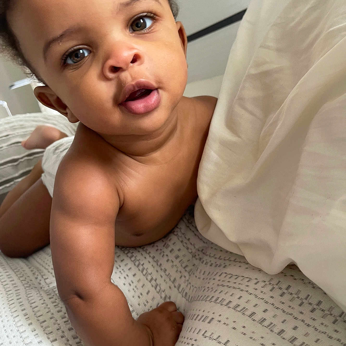 Matthew W. is registered to the contest to win money with this photo: arm, baby, bed, blanket, child, closeup, crawling, curly_hair, cute, expression, eyes, face, hand, indoors, infant, person, pillow, skin, soft_lighting, young