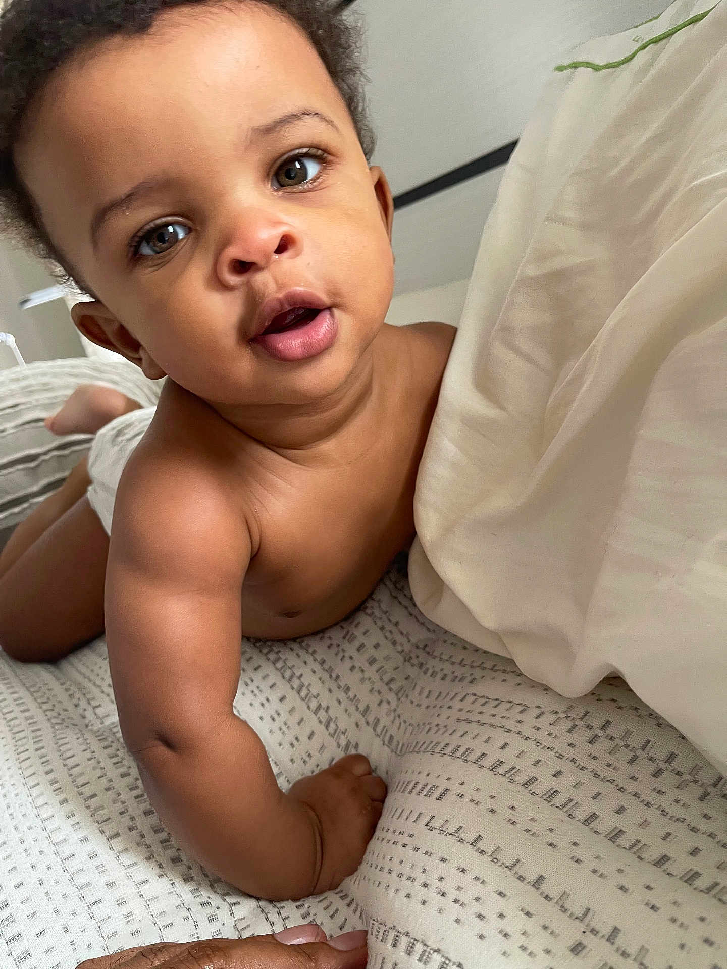 Matthew W. is registered to the contest to win money with this photo: baby, child, infant, face, eyes, skin, arm, hand, blanket, bed, pillow, curly_hair, expression, closeup, indoors, crawling, cute, person, young, soft_lighting