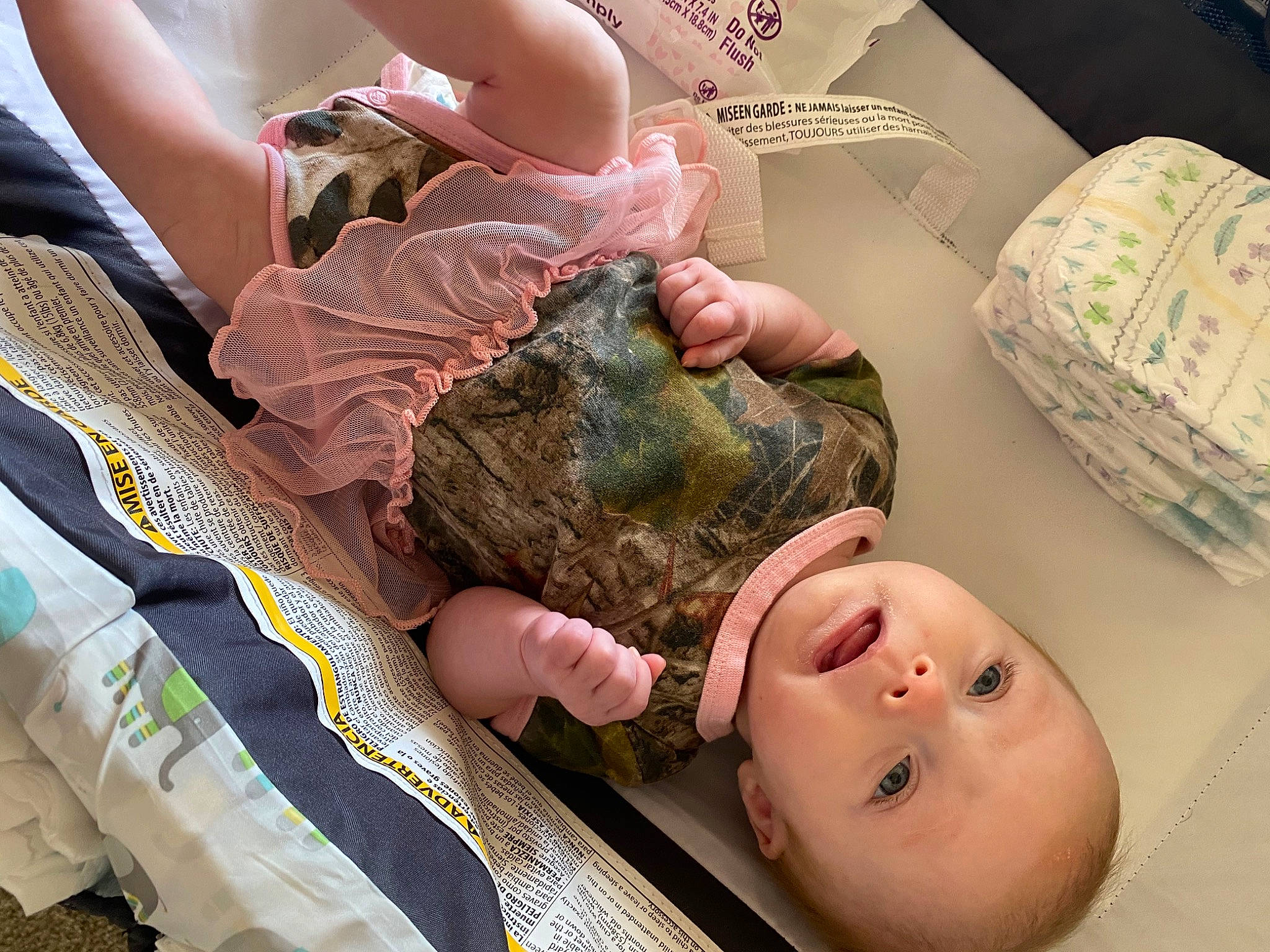 Kinslee is registered to the contest to win money with this photo: arm, baby, baby_toddler_clothing, bed, camouflage, child, comfort, finger, flesh, gesture, joint, military_camouflage, military_uniform, pattern, person, room, skin, soldier, textile, thumb