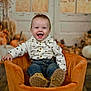 baby, child, smile, happy, suspenders, jeans, orange_chair, indoor, autumn, pumpkins, background, plush_chair, cute, portrait, sitting, person, floor, shirt, footwear, decor