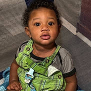 Rishown joined the competition — help win amazing prizes! toddler, child, playpen, green_overalls, gray_shirt, blanket, indoor, curly_hair, big_eyes, baby, cute, sitting, person, portrait, young_child, clothing, fabric, comfort, baby_toy, playtime