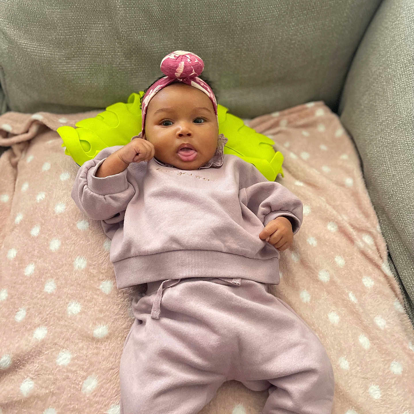 Zahra joined the competition — help win amazing prizes! baby, blanket, casual, child, couch, cozy, cute, happy, headband, indoor, infant, lying_down, person, pillow, pink_clothing, polka_dots, relaxing, smiling, soft_texture, tongue_out