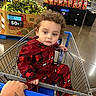 toddler, child, shopping_cart, grocery_store, pajamas, spiderman, curly_hair, hand, tattoo, produce, corn, snacks, floor, person, retail, clothing, orange_socks, face, expression, supermarket
