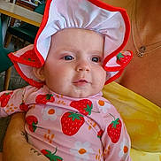 Rosa joined the competition — help win amazing prizes! baby, child, person, infant, hat, strawberry_pattern, flower_pattern, clothing, drool, hand, fan, yellow_top, indoor, table, chair, window, reflection, face, portrait, holding