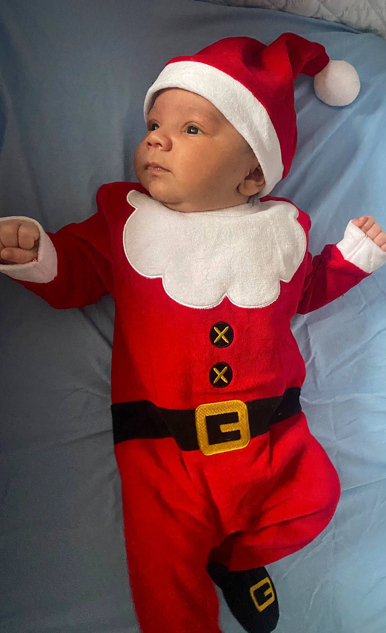 Zak is registered to the contest to win money with this photo: arm, baby, baby_toddler_clothing, cap, christmas, costume_hat, event, face, fictional_character, glove, happy, hat, headgear, headwear, holiday, jacket, outerwear, person, red, santa_claus