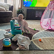 Macie Rae joined the competition — help win amazing prizes! toddler, child, indoor, living_room, toy, blanket, chair, carpet, television, plant, window, curtain, pink_pajamas, play_tent, colorful, floor, couch, smiling, baby, furniture