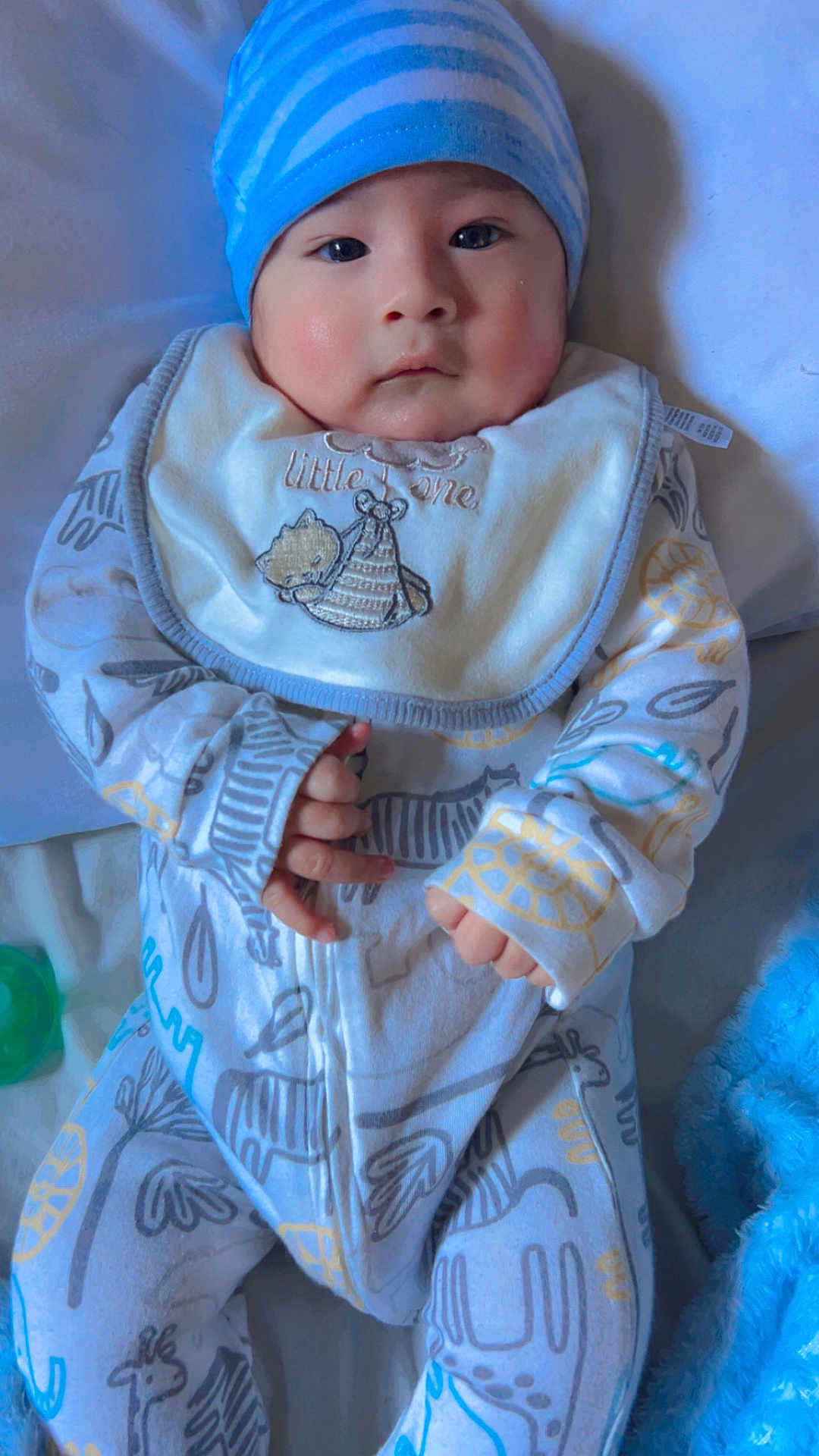 Jhayco joined the competition — help win amazing prizes! baby, child, infant, blue_hat, bib, onesie, animal_pattern, hand, face, cheeks, soft_toy, blanket, bed, sleepwear, cute, portrait, indoors, cozy, newborn, clothing
