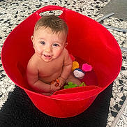 Naël participe au concours pour gagner de l'argent avec cette photo : baby, bath_toys, black_rug, child, cute, floor, happy, head, indoor, person, playful, red_bucket, sitting, skin, smiling, tile_floor, toy_duck, toy_fish, toy_pig, water