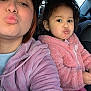 Mia is registered to the contest to win money with this photo: person, child, adult, selfie, car_interior, pink_jacket, hoodie, pigtails, earrings, puckered_lips, portrait, window, seat, seat_back, hair, cozy_clothing, family, matching_outfit, toddler, cute_expression