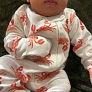 Jakobee joined the competition — help win amazing prizes! baby, infant, onesie, crab_pattern, sleepwear, blanket, soft_texture, cute, child, face, portrait, indoors, resting, comfortable, expression, newborn, human, sitting, clothing, skin