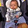 baby, sleeping, car_seat, plaid_shirt, denim_pants, brown_shoes, infant, child, closed_eyes, seatbelt, warning_label, clothing, cute, resting, indoor, person, young_child, head_support, comfortable, peaceful